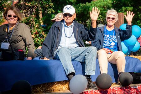 Alums riding on a float during the Homecoming Parade.