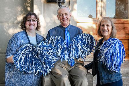 Foundation staff holding pom poms in front of TJ Majors.